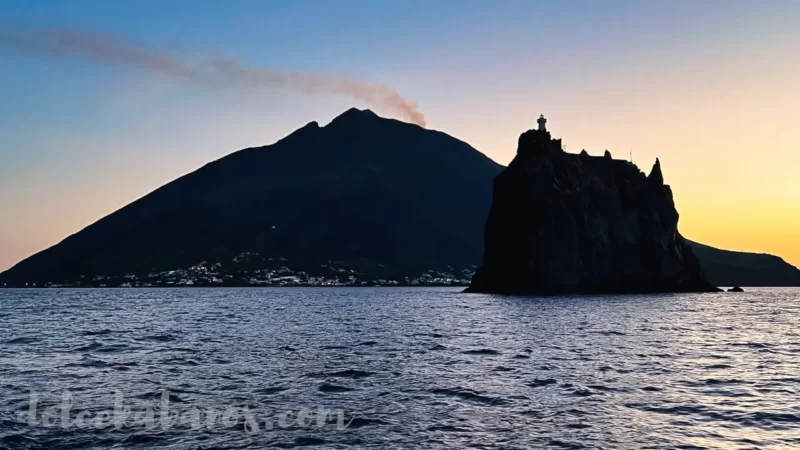 widok na wysepkę Strombolicchio i wulkan Stromboli w tle podczas zachodu słońca